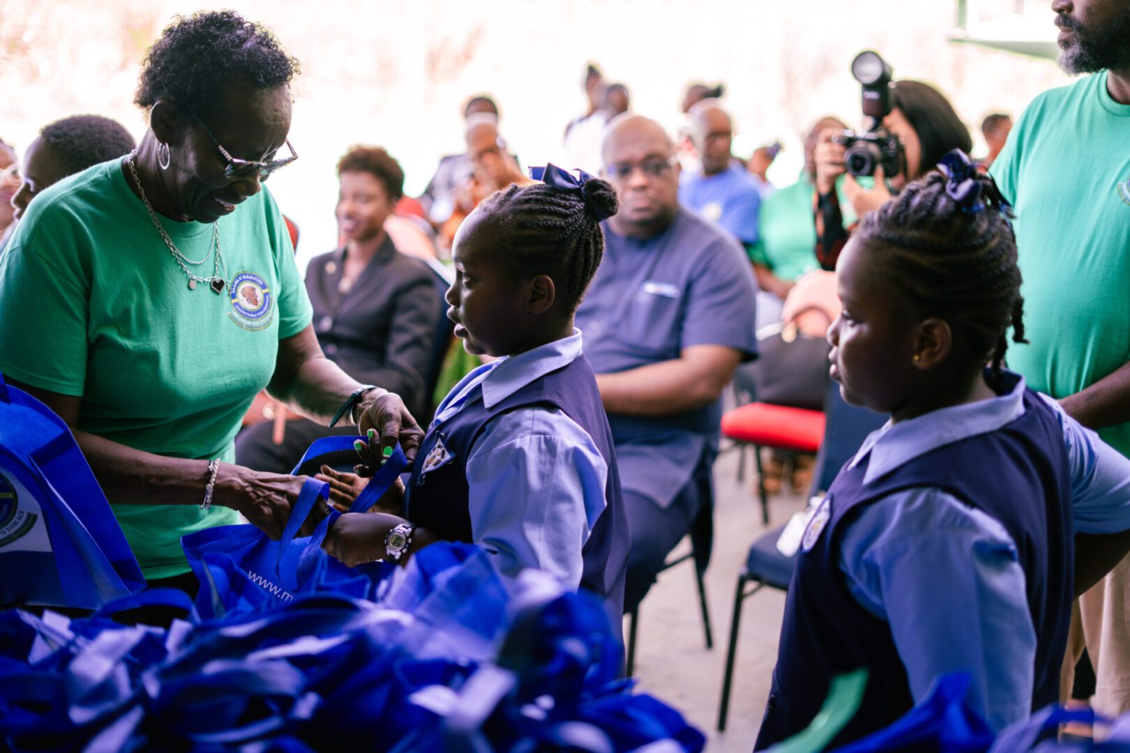 Children receiving gifts from a woman in a community event.