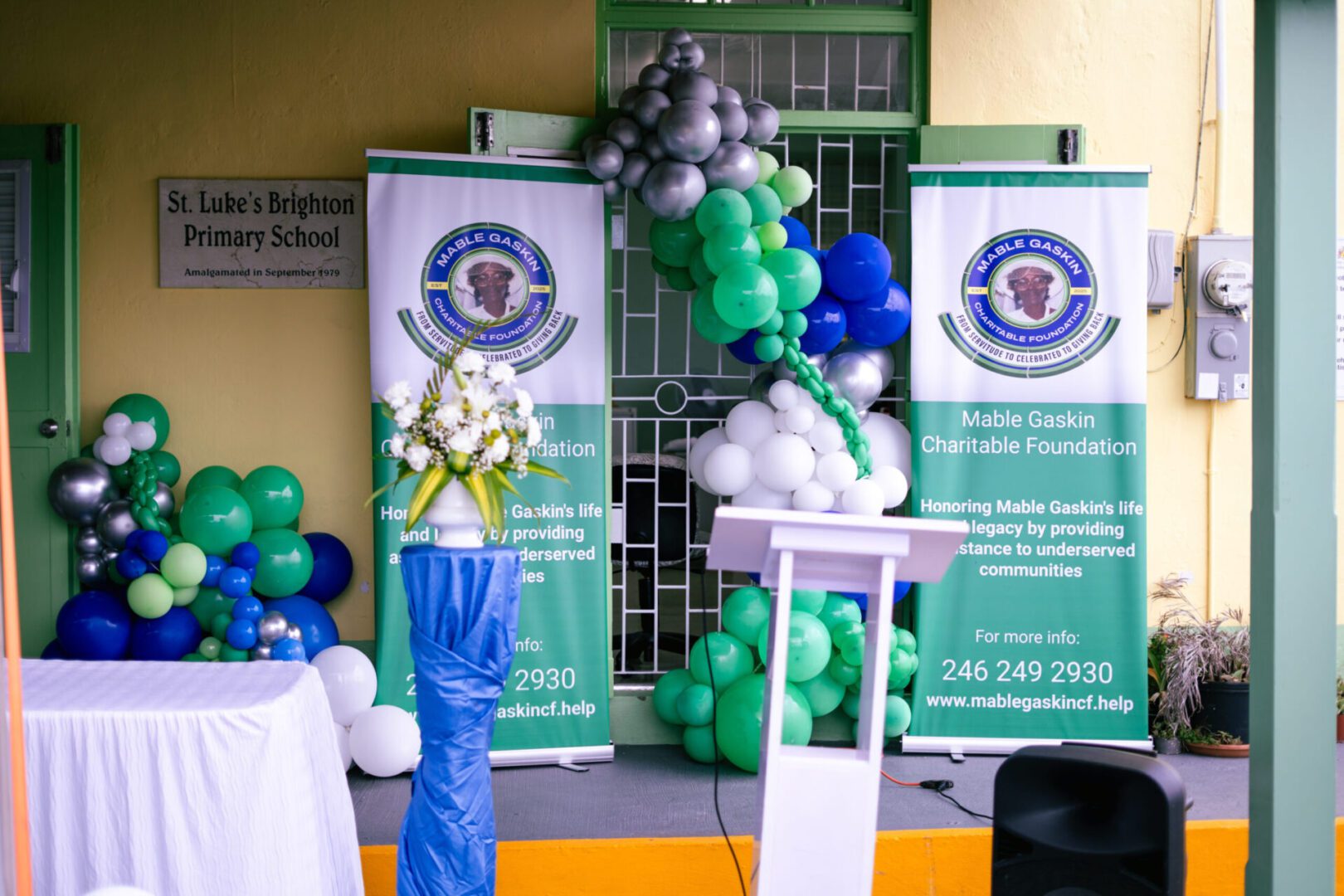 Decorative balloon arrangement at a celebratory event with banners and a podium.